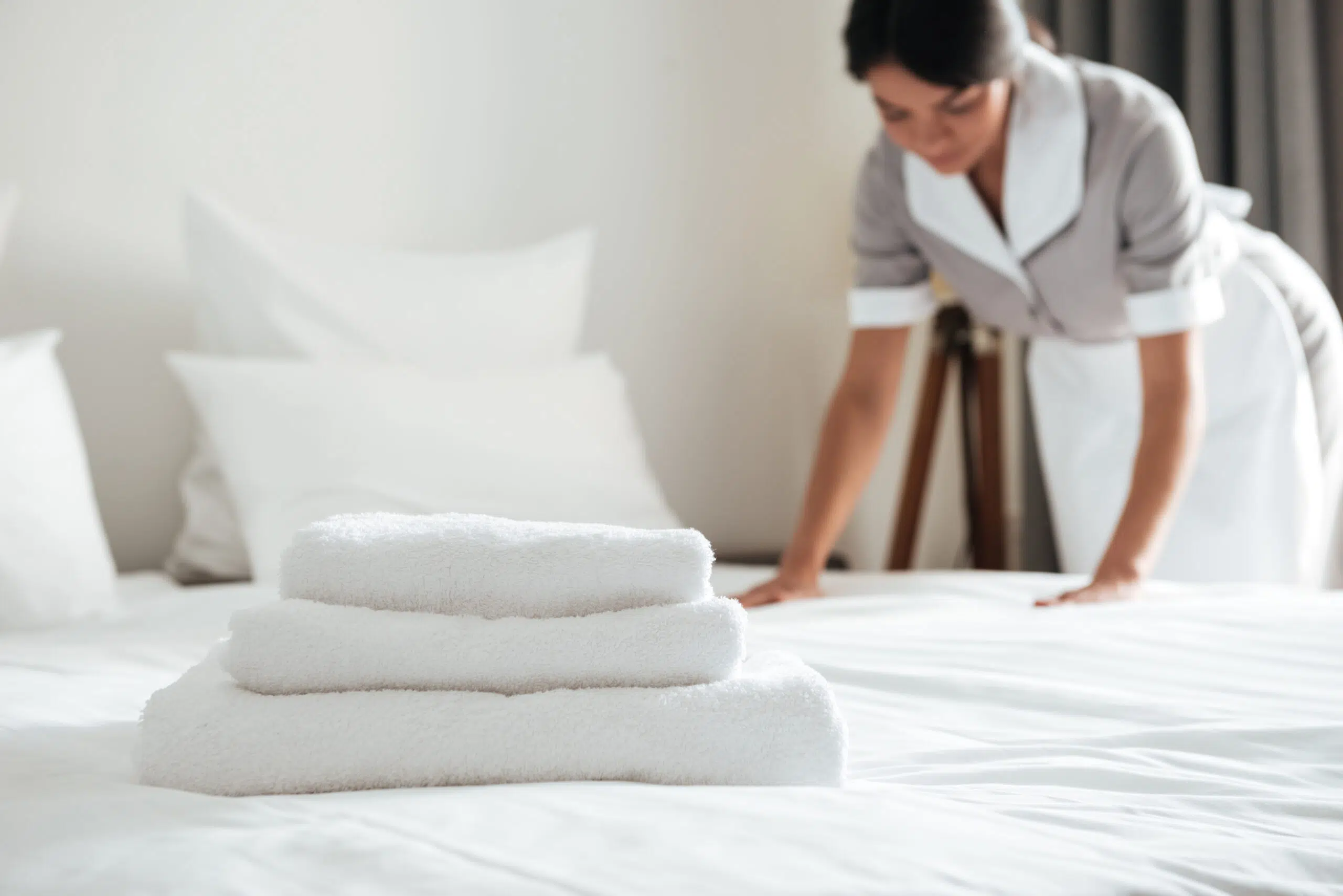 young hotel maid setting up pillow bed scaled.jpg
